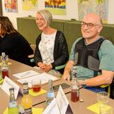 Mehrere Mitglieder vom Beirat Selbsthilfe sitzen gemeinsam am Tisch.