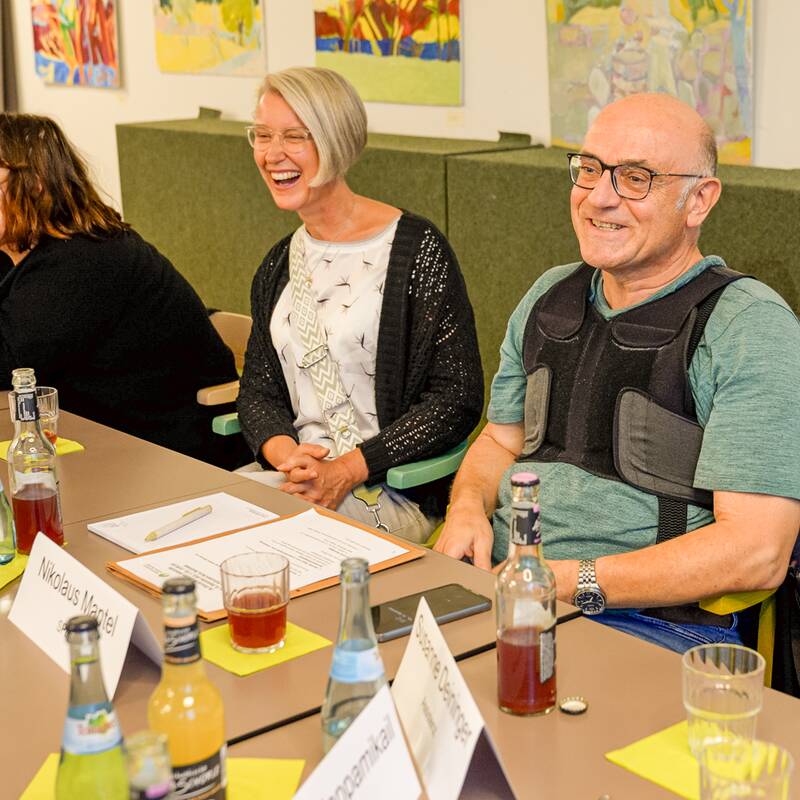 Mehrere Mitglieder vom Beirat Selbsthilfe sitzen gemeinsam am Tisch.