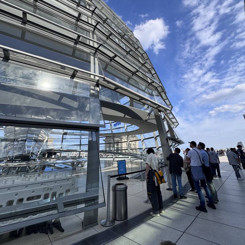 Eine Gruppe von Menschen befindet sich auf der Dachterrasse der Reichstagskuppel in Berlin. 