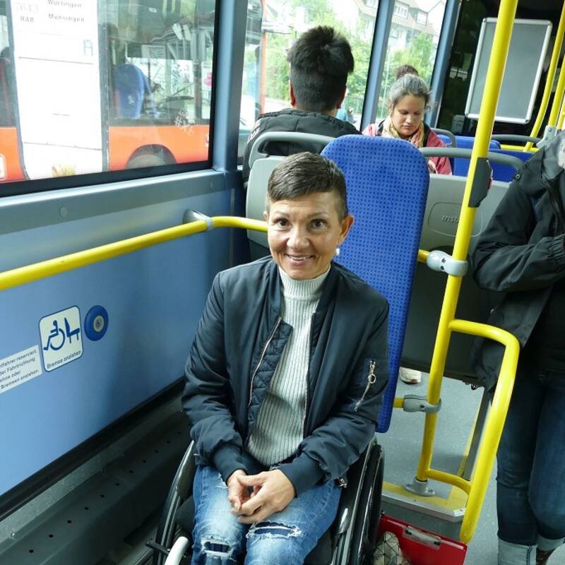 Eine lachende Rollstuhlfahrerin auf dem Rollstuhlplatz in einem Bus
