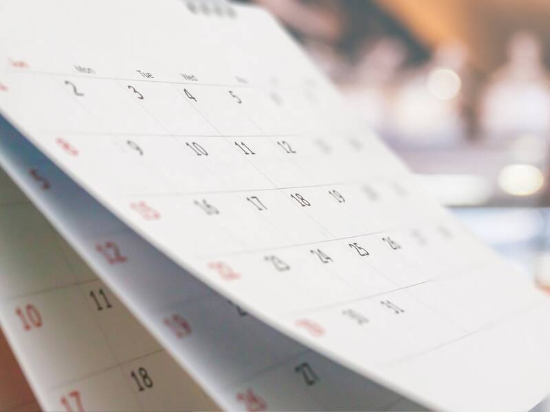 Ein aufgeschlagener Kalender zeigt mehrere Monate auf verschwommenem Hintergrund.