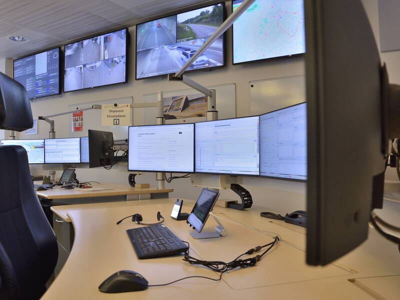 Arbeitsplatz eines Disponenten in der Intergierten Leitstelle von Feuerwehr und Rettungsdienst in Reutlingen. Er besteht aus einem Schreibtisch mit mehreren Computermonitoren und Überwachungsbildschirmen, Tablet, Headset und Schreibtischstuhl.
