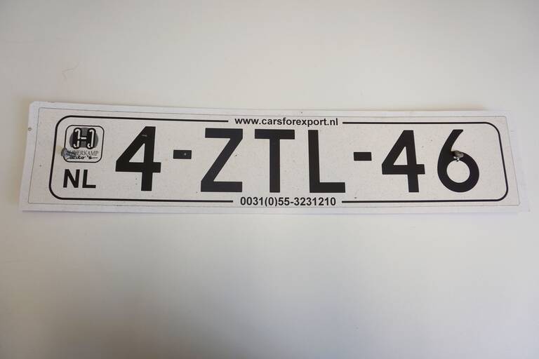 Ein weißes Autonummernschild aus dem Ausland. Darauf stehen die Buchstaben und Nummern 4-ZTL-46. Das Autonummernschild liegt auf einem weißen Untergrund.