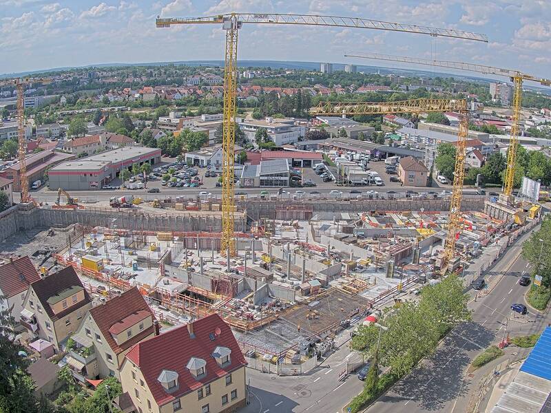 Eine Baugrube von oben. In der Grube stehen zwei gelbe Kräne.